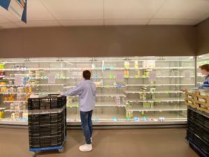 man in white dress shirt and blue denim jeans standing in front of white shelf