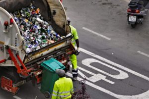 people collecting trash in garbage truck