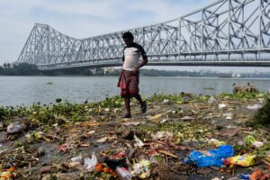 woman in white shirt and red skirt standing on brown dried leaves near bridge during daytime