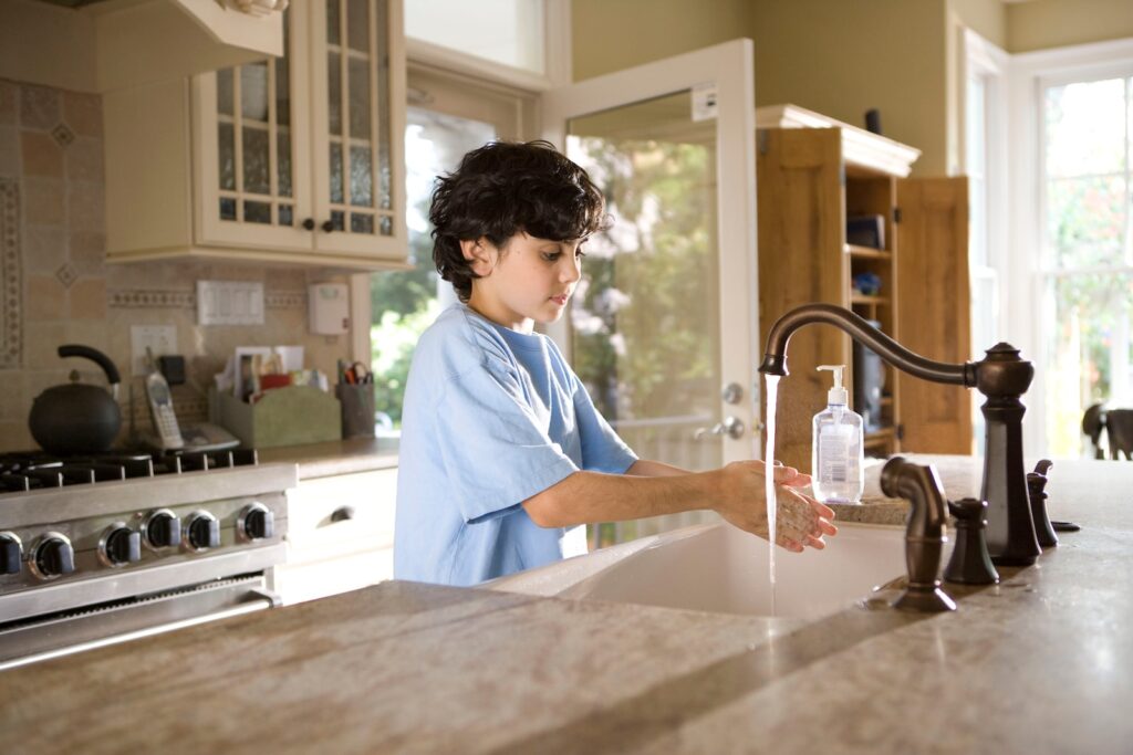 boy in blue polo shirt standing in front of sink