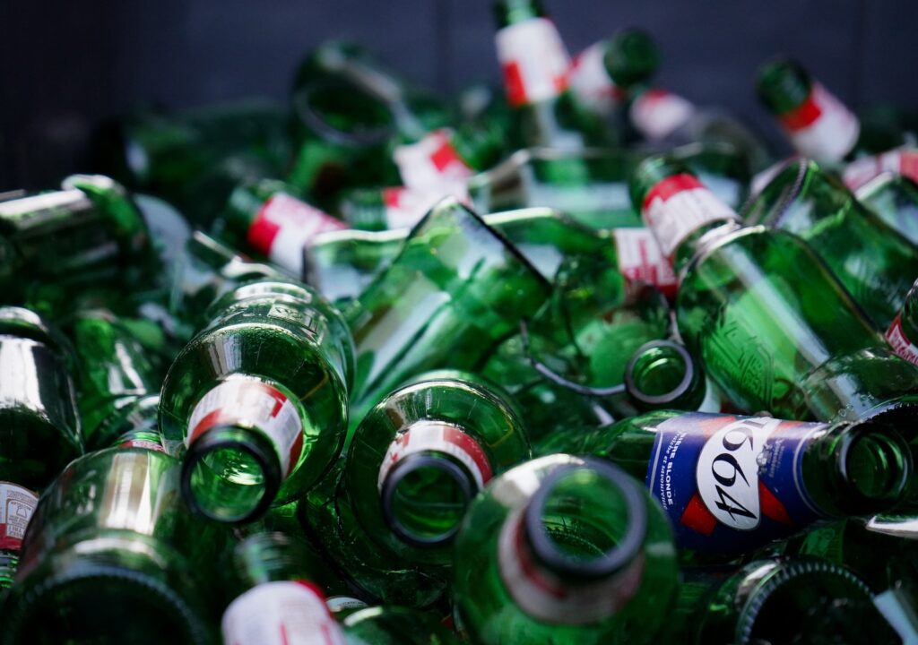 a pile of empty green beer bottles
