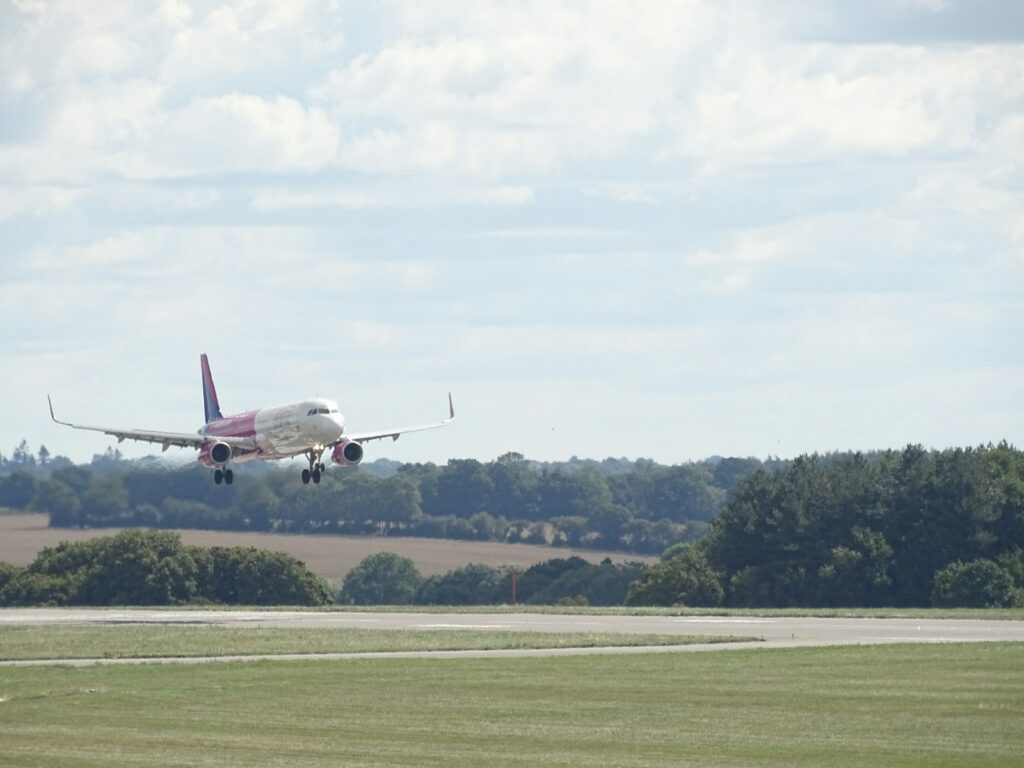 a large passenger jet flying over a lush green field