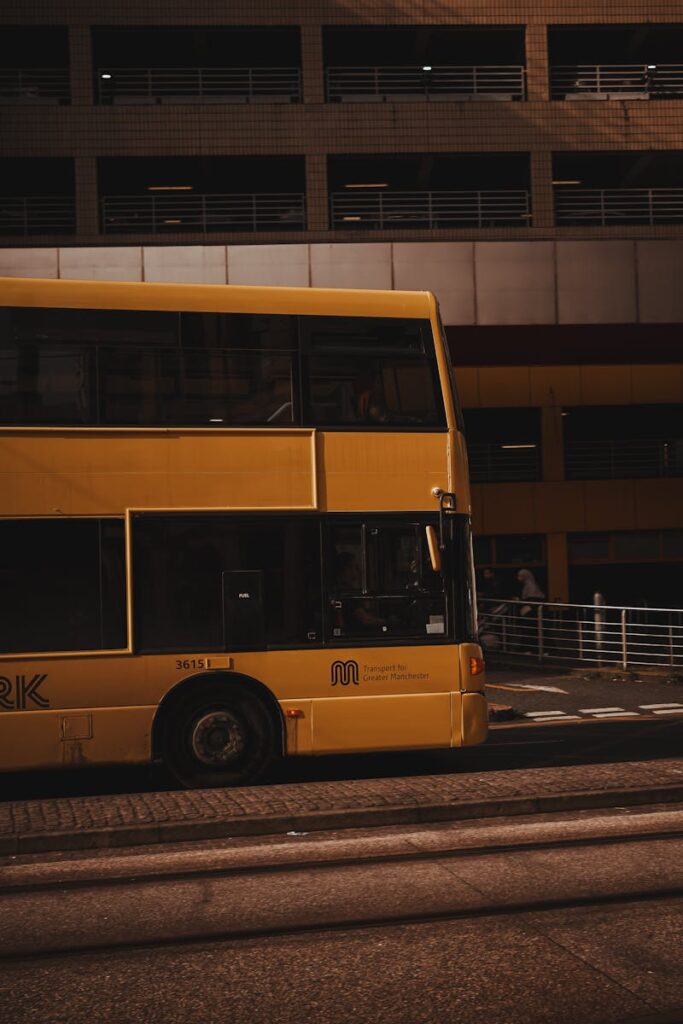 A vibrant yellow double-decker bus in a city street, showcasing urban transportation in Manchester, England.