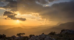 the sun is setting over a mountain range