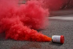 A red smoke bomb sitting on the side of a road