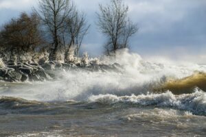 A painting of waves crashing on a rocky shore