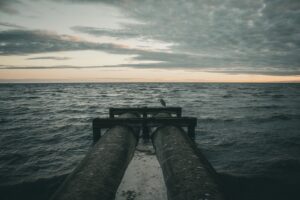 Two large pipes extend into the choppy ocean water.