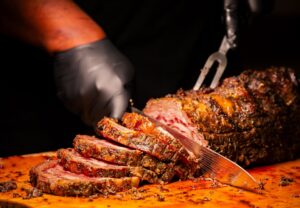 A person cutting a large piece of meat on a cutting board