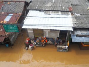 Flooding submerges houses, people gather to seek shelter.